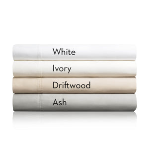 Four cotton blend sheets for fire department mattresses folded on top of one another, labeled with their respective color white, ivory, driftwood or ash 